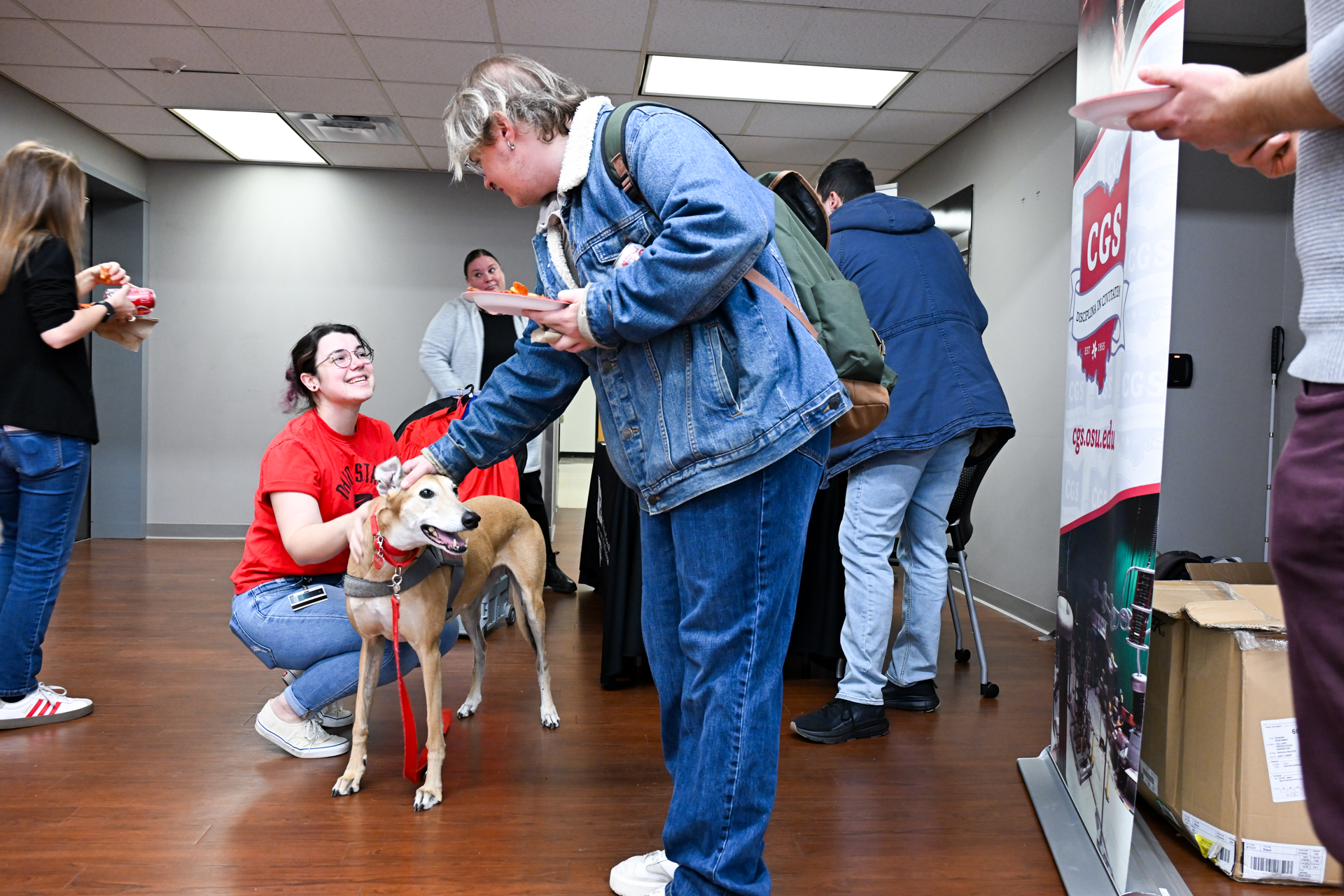 2 grad students enjoying petting a dog from buckeye paws