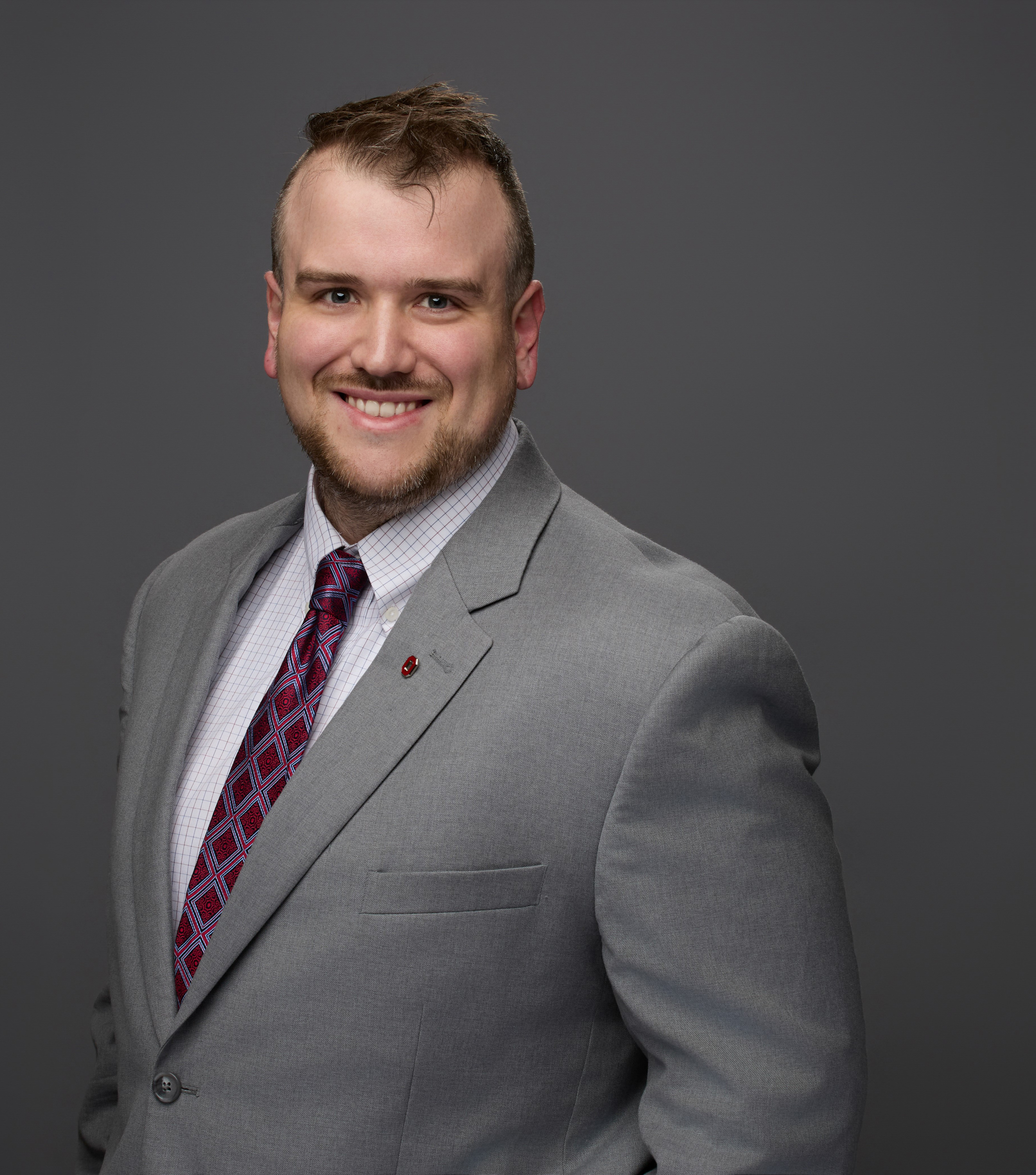 Portrait of TJ Carpenter in Grey Suit and Scarlet Tie