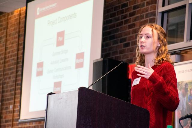 Graduate student Abby Mills behind podium presenting presentation.