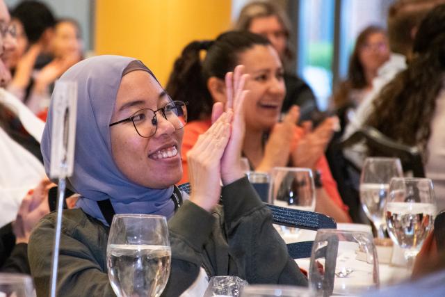 Graduate student applauding announcement of colleagues as award recipients at the Hayes Forum Awards Banquet.