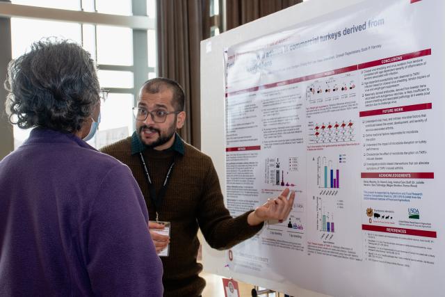 Graduate student and faculty member engaging around the student’s research at the Hayes Forums Poster Presentation Competition.