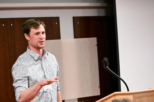 Biochemistry graduate student Andrew Savidge presenting at a podium
