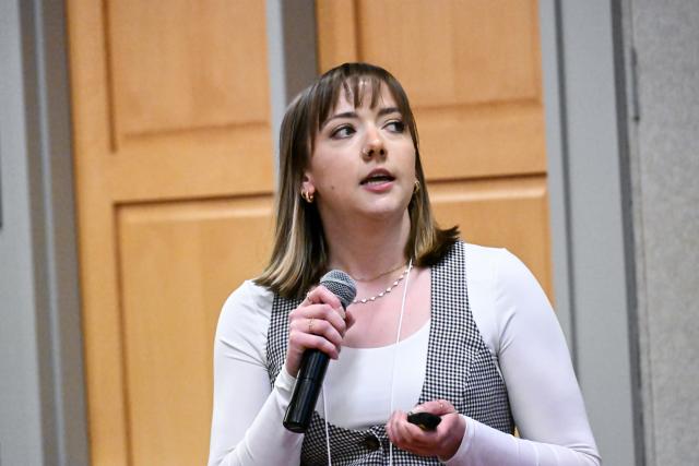 DB graduate student Jessica Herstine presenting holding a microphone