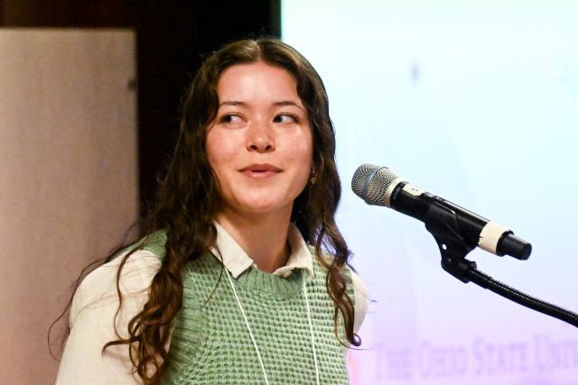 Biophysics graduate student Mia Kordowski presenting at a microphone