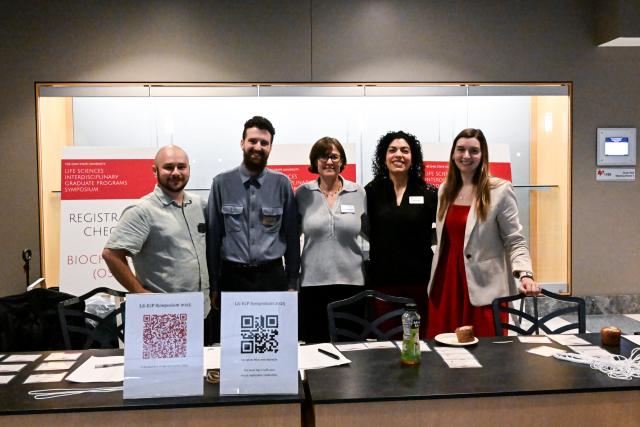 5 IGP Coordinators at LS IGP Symposium standing together at the registration table