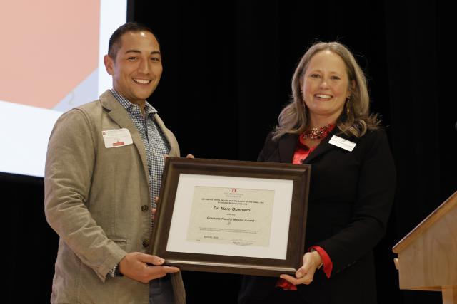 Marc Guerrero receiving the Graduate Faculty mentorship award certificate from Dean Stromberger