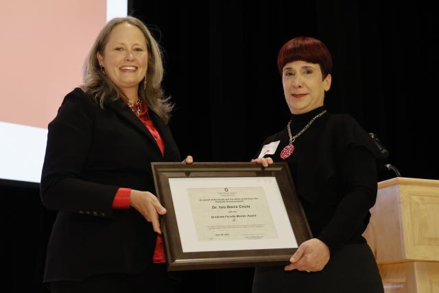 Isis Barra Costa receiving the Graduate Faculty mentorship award certificate from Dean Stromberger