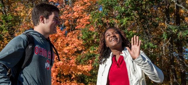 Two students conversing under trees