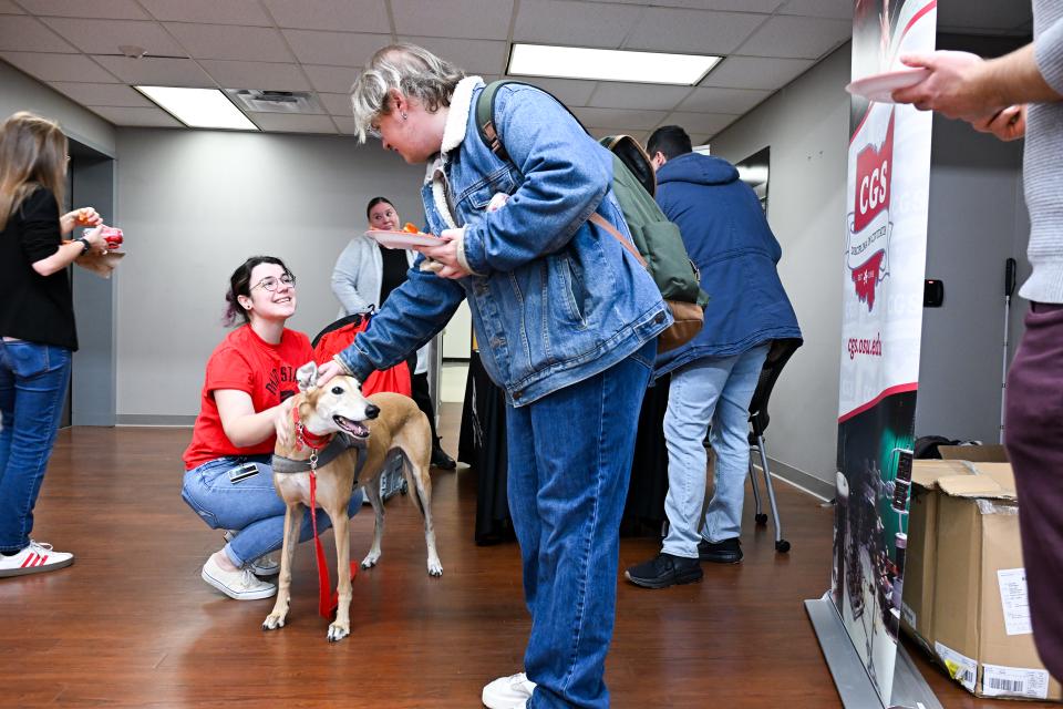2 grad students enjoying petting a dog from buckeye paws