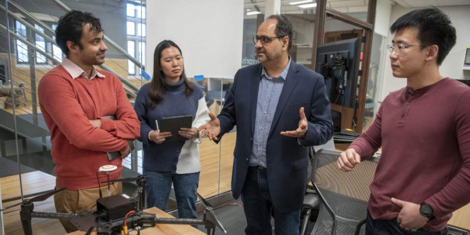Professor and students talking around drone