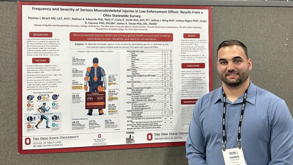 Thomas Beach standing next to a research poster as a poster presentation