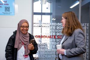 Graduate student and Ohio State Dean smiling and drinking coffee at the 2024 Donuts with the Deans Event