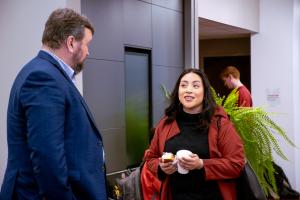 Graduate student holding her coffee while speaking to an Ohio State Dean at the 2024 Donuts with the Deans event.