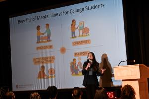 Charis Stanek on a stage presenting in front of a presentation