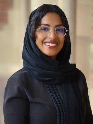 A photo of Aidah Aljuran smiling wearing glasses and a black dress