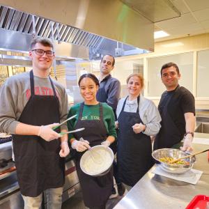 Grad students posing in kitchen whisking ingredients
