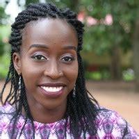 A photo of Augusta Irele smiling wearing a multi-colored blouse.