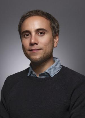 A photo of Martin Fuchs smiling wearing a black sweater over a blue dress shirt.