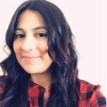 A photo of Andrea Garcia smiling wearing a red and black flannel.