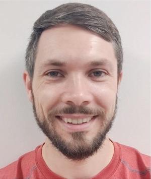 Photo of Jacob Hopkins smiling in red shirt.