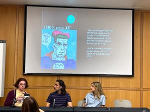 Three graduate students at a table presenting on Comics versus Art