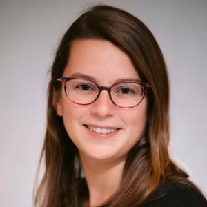 A photo of Kelly Karch smiling wearing glasses and a black shirt.