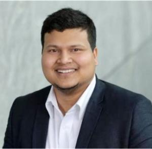 Photo of Wasiur Khuda Bukhsh smiling wearing a dark blue blazer and white dress shirt.