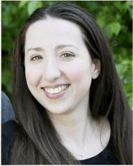 Kathryn Kroeper smiling wearing a black blouse with green foliage in the background.