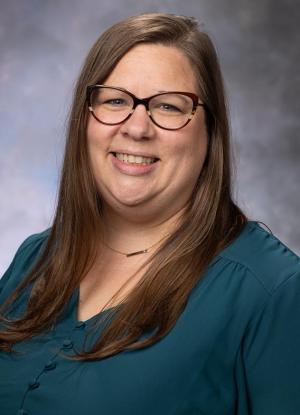 A photo of Lisa Robinette smiling wearing a turqiouse blouse and glasses.