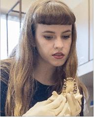 A photo of Katie McGrath in a lab holding dental models