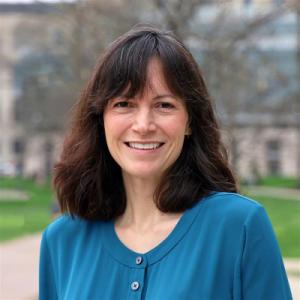 A picture of Megan Roberts smiling at the camera wearing a blue shirt.