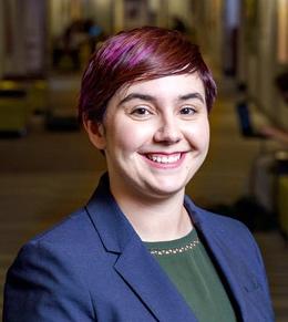 A photo of Nicole Pfiester Latham smiling wearing a blue blazer and green blouse.