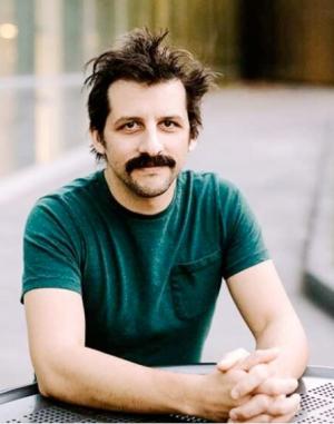 Steven Prohira smiling at the camera wearing a green tshirt.