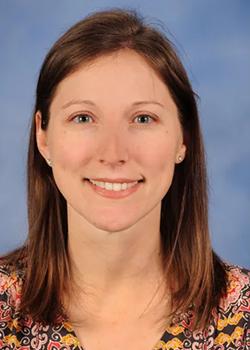 Jenessa Winston Portrait with brown hair a floral shirt on a marbled blue background