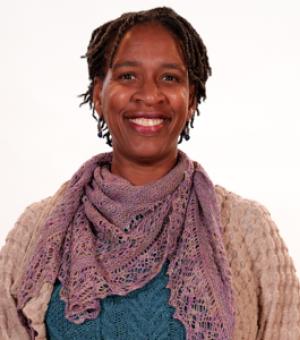 Portrait of Maria Miriti in a tan sweater with mauve scarf